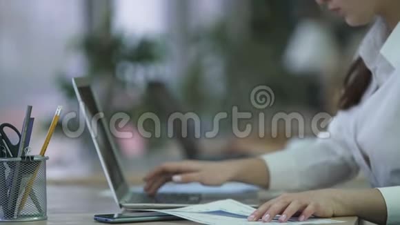 妇女从纸质文件中插入笔记本电脑数据在办公室编写报告视频的预览图