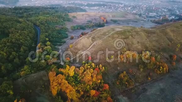秋天的早晨艾里尔视频片段有路的山和五颜六色的树背景上的村庄冷的颜色视频的预览图