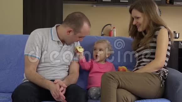 带着小宝宝的家人吃红鲜苹果坐在沙发上4K视频的预览图