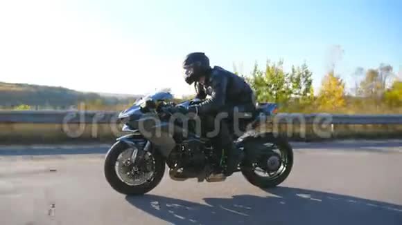 戴着头盔的年轻人骑着高速公路上的现代摩托车摩托车手在乡间公路上骑摩托车视频的预览图