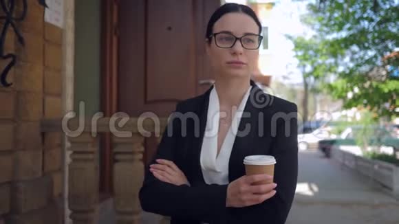 生活中的压力戴眼镜的年轻商务女性患有抑郁症手里拿着咖啡走在城市的街道上视频的预览图