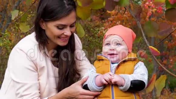 快乐的童年和母亲妈妈和孩子在秋天公园在黄树的背景下进行有趣的户外特写视频的预览图