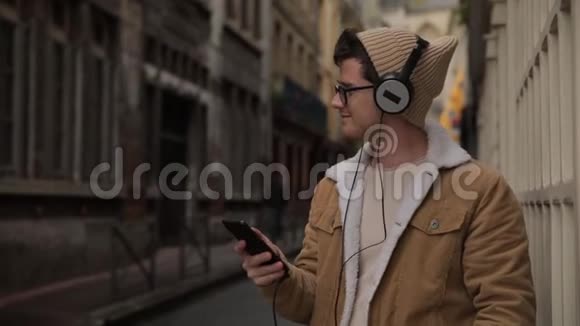 笑容可掬帅哥戴着耳机用智能手机听音乐在老城街头跳舞视频的预览图