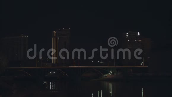 夜晚的城市景观河上有一座桥和移动的汽车库存录像美丽的夜城筑堤视频的预览图