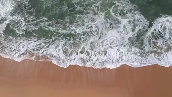 在葡萄牙的沙滩上金色的沙滩和绿色的蓝色的大海上高空的海浪拍打着视频的预览图