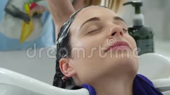 洗头女士在美容院洗头时享受理发师按摩视频的预览图