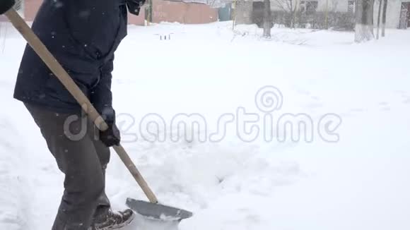 除雪男的手里拿着铲子在冬天从雪堆里清理院子视频的预览图