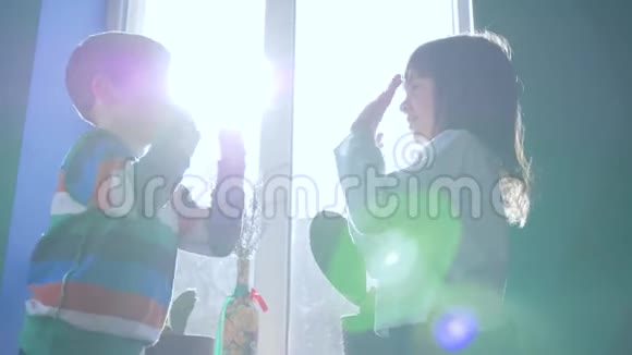快乐的童年小朋友在房间里背对着窗户用阳光拍拍手视频的预览图