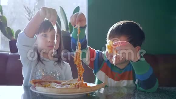 快乐的童年快乐的朋友在靠近窗户的比萨饼店午餐时吃垃圾食品视频的预览图