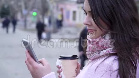 在互联网上聊天女性带着智能手机和一杯咖啡在户外近距离与朋友交流视频的预览图