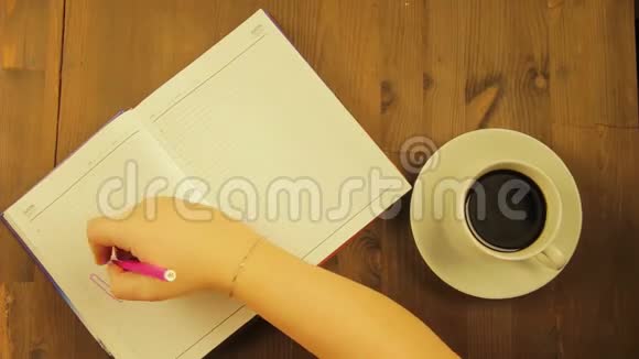 女孩在日记里用一支粉红色的毡尖笔和喝咖啡来写爱这个词时间跨度视频的预览图
