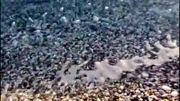 海在沙滩上洗卵石滚石声音响一片石滩的特写镜头小浪撞击卵石视频的预览图