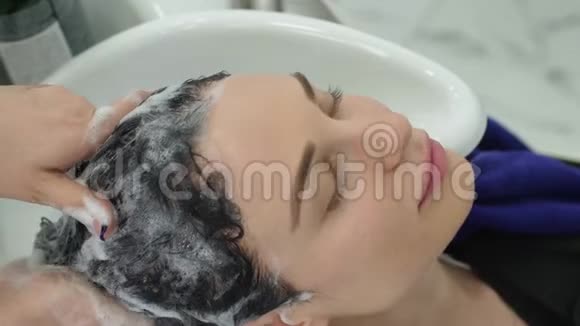 美容美发店理发师用美容师满意女士的专业洗发精洗头视频的预览图