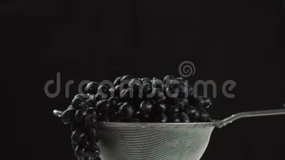 在视频中我们看到葡萄在筛子中水从顶部开始下降相机从上到下移动黑色背景视频的预览图