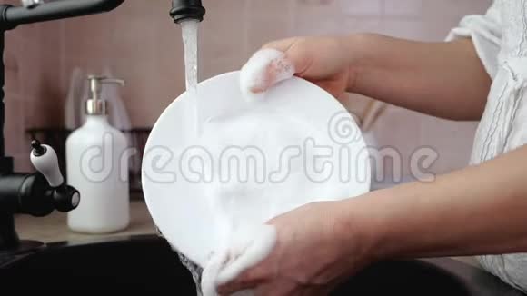 女人用手在厨房水槽里冲洗盘子视频的预览图