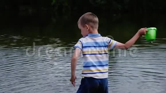 小男孩怒气冲冲地把桶里的水倒进河里儿童自然游戏视频的预览图