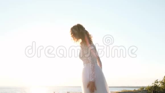 夏天穿着婚纱的欧洲新娘在海滩上的夕阳下跳跃视频的预览图