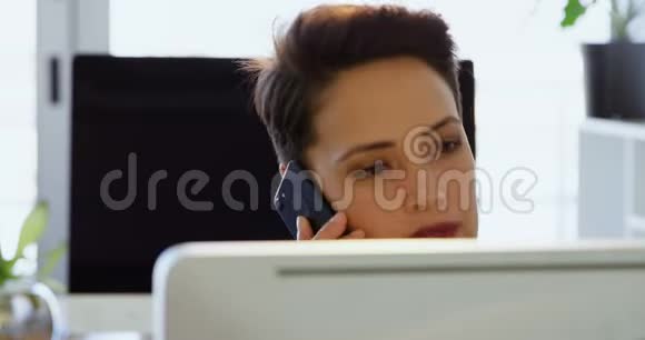 高加索女商人在一间现代化办公室的办公桌上用手机交谈的前景视频的预览图