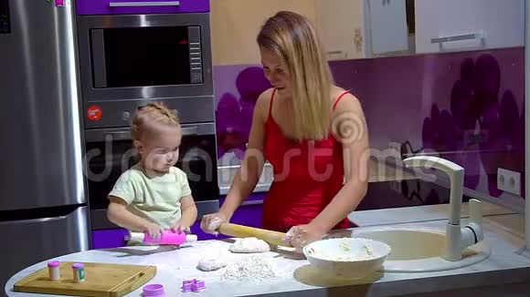 一位带着一个小女儿的年轻母亲正在准备披萨面团视频的预览图