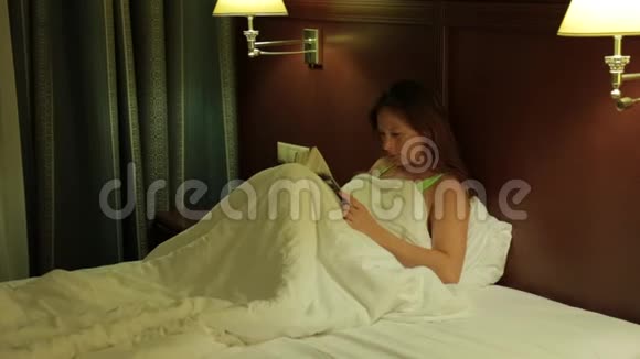 一个年轻的女人在入睡前热情地看书夜晚视频的预览图