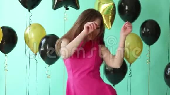 年轻迷人的成年女孩穿着蓝色背景的优雅粉红色连衣裙视频的预览图