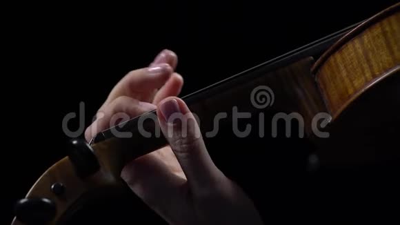 一位音乐家用手指捏紧小提琴黑色背景视频的预览图