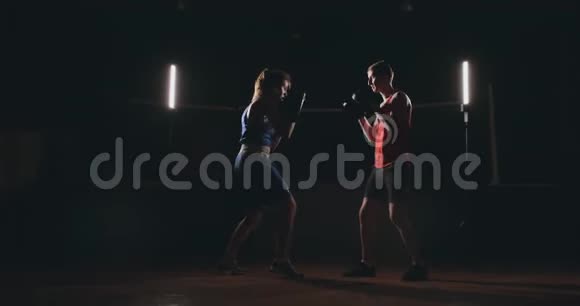 女拳击手在烟雾弥漫的健身房里用拳击手套打聚焦拳视频的预览图
