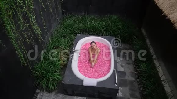 女孩坐在花瓣浴缸里室外温泉浴轻松度假视频的预览图