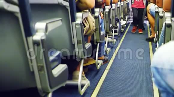 孩子在飞机的机舱里行走只有腿是可见的飞机内部有乘客在座位上视频的预览图