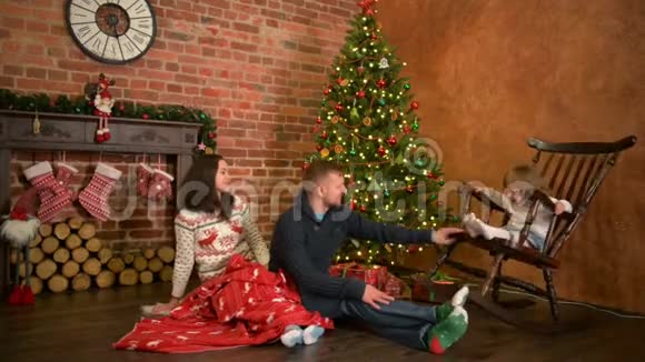 家人平安夜在壁炉家长和小孩子开启圣诞礼物带礼品盒的儿童生活起居视频的预览图