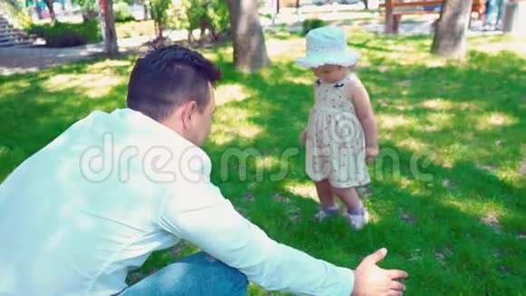 一个小女孩慢慢地走在房子附近的绿色草坪上她的父亲微笑着靠近父亲转身走开了视频的预览图