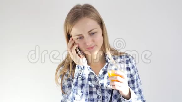 带着一杯果汁的年轻女子在手机上交谈视频的预览图