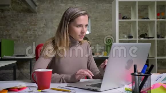 为快乐的白种人女办公室职员在笔记本电脑上打字并因成功而感到兴奋的特写照片视频的预览图
