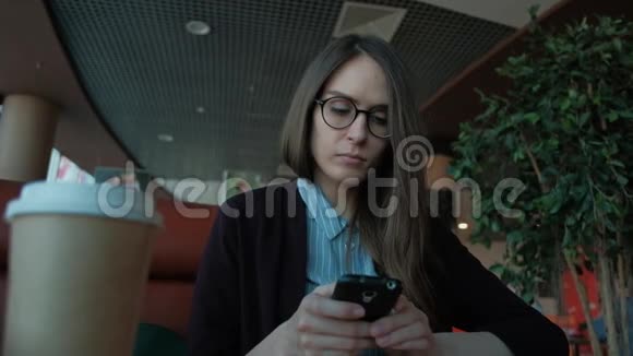 慢动作可爱的女性使用智能手机和在咖啡馆喝咖啡视频的预览图