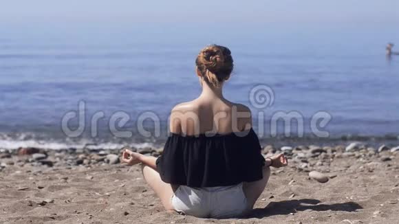 年轻女子在海上海洋海滩上以莲花姿态冥想和谐与沉思美丽的女孩在海上练习瑜伽视频的预览图