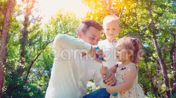 父亲在公园给儿子和小女儿吹肥皂泡生活方式家庭观念视频的预览图