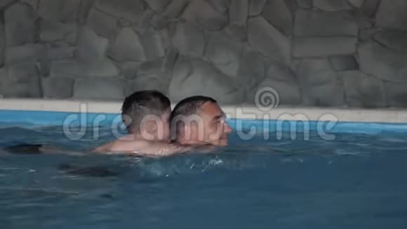 一个幸福的家庭父子俩在游泳池里玩耍视频的预览图