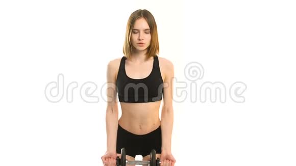 一位穿着运动服穿着哑铃在白色背景下锻炼的年轻健身女子的肖像视频的预览图