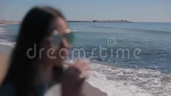 海边一个年轻女孩模糊的形象她戴上墨镜开始看清视频的预览图