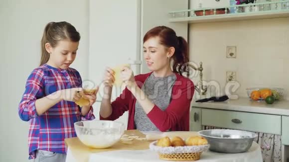快乐的妈妈和有趣的女儿一起在厨房做饭时用面团做傻脸视频的预览图