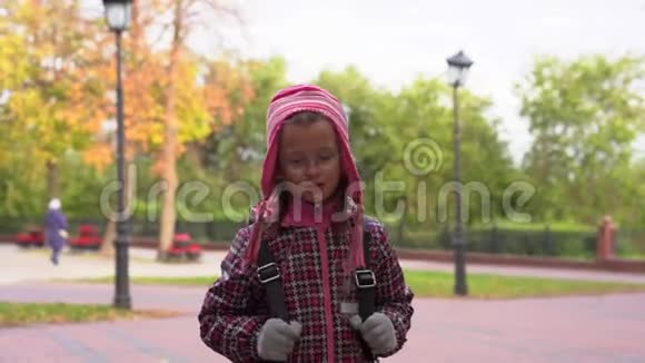 女孩在公园的人行道上散步一个女孩放学后在公园里散步视频的预览图