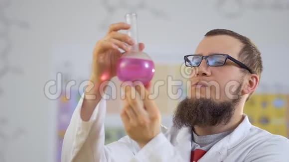 实验室助理研究瓶中的粉红色液体视频的预览图