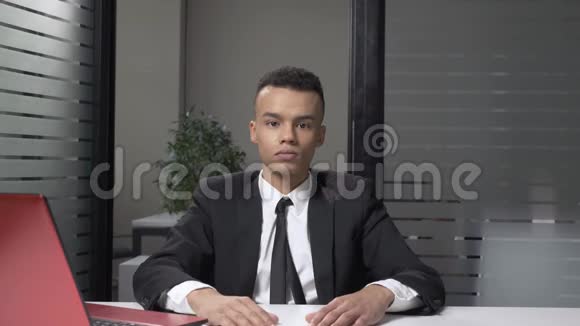年轻成功的非洲商人穿着西装坐在办公室里表现出沉默的迹象60英尺视频的预览图
