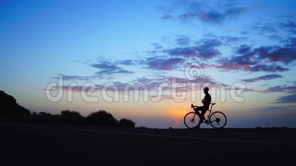 剪影男在公共公园骑自行车以获得日落背景下的健康视频的预览图