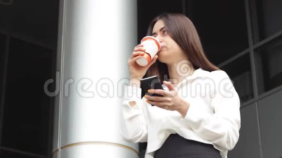 女人用智能手机喝热饮料视频的预览图