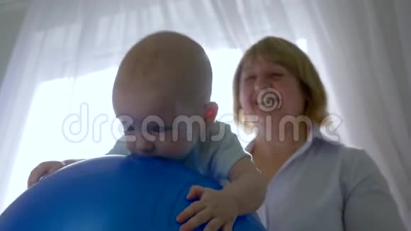 专业治疗师把新生儿抱在背光的充气蓝球上视频的预览图