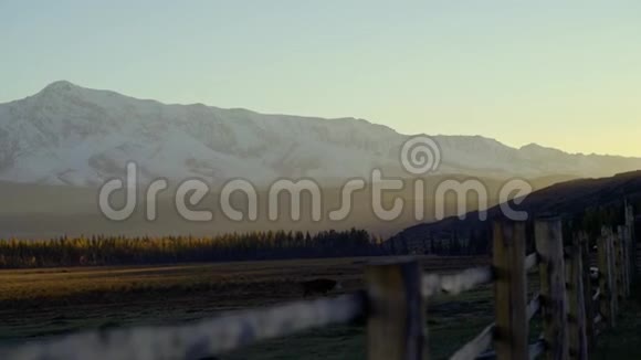 晚上在山里太阳是低的美丽的光前景是一座木栅栏一座白雪覆盖的山视频的预览图