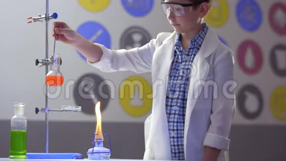 学校男生在实验室的烧瓶里混合橙色液体视频的预览图