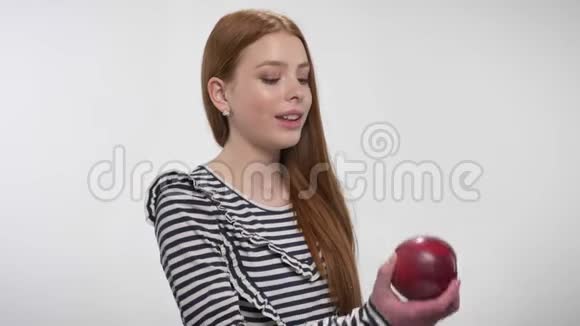 年轻的姜妹正在咬红苹果提供它交流理念白色背景视频的预览图