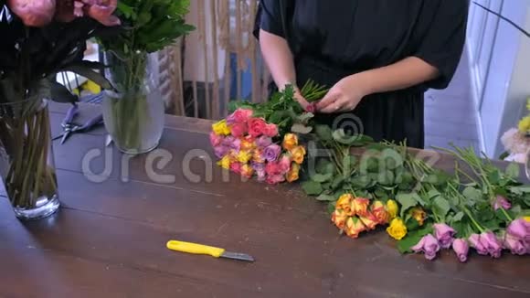 花商女人在商店里用五颜六色的小玫瑰做花束双手特写视频的预览图